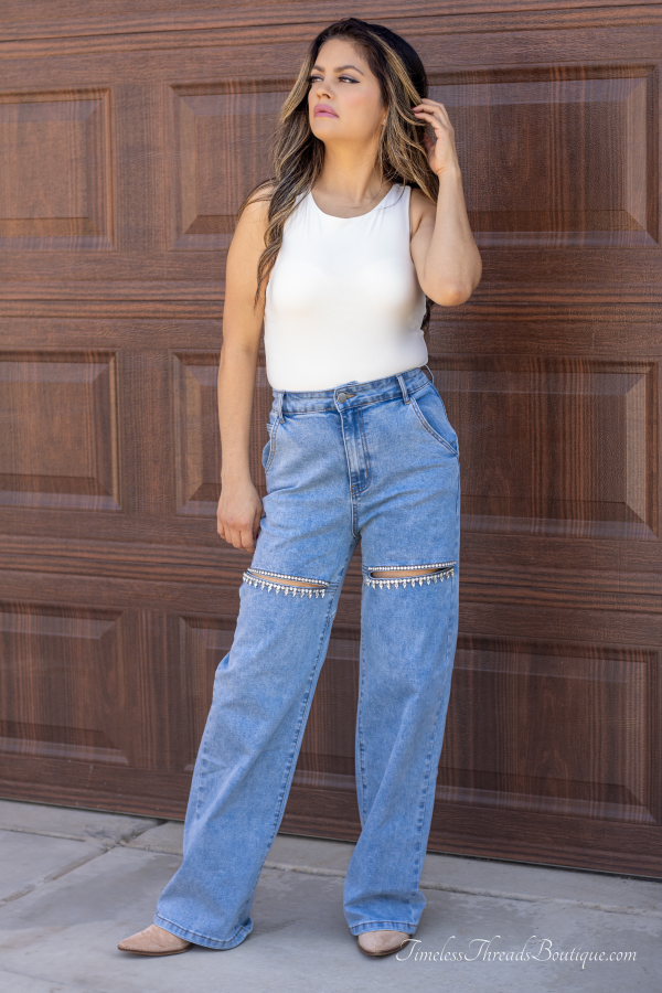 "Shimmer Cut Light Washed Rhinestone Front Denim Jeans with above-the-knee slits adorned with rhinestones and a heart-shaped detail on the back, offering a trendy and glamorous look."