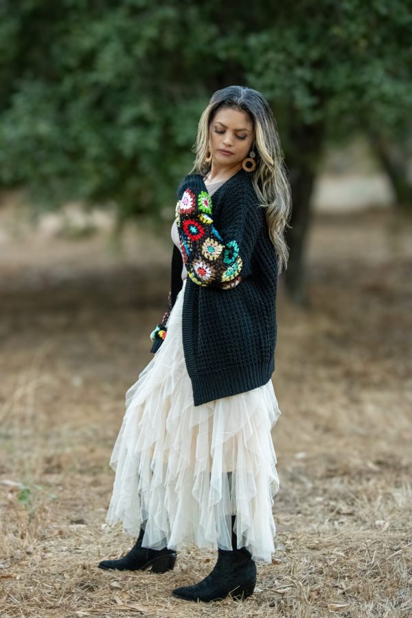 A cozy black knit long sleeve cardigan featuring vibrant multi-colored patterns, perfect for fall layering. This stylish cardigan is ideal for pairing with boots and adds a chic touch to any outfit.