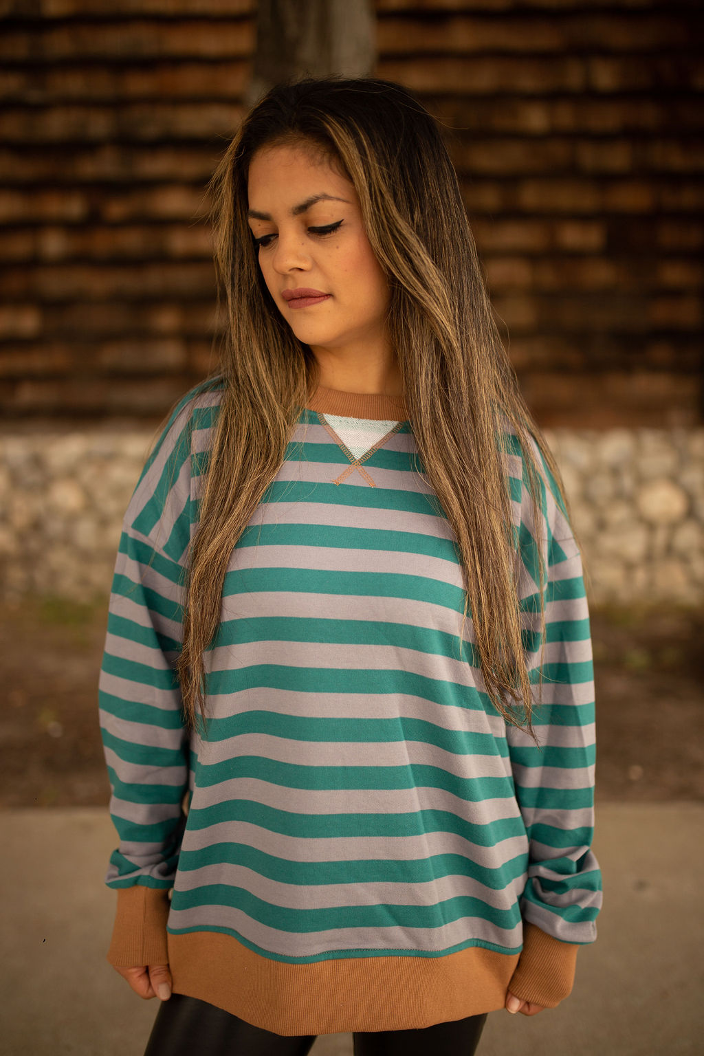 Teal and gray striped sweatshirt with caramel ribbed cuffs and hem, shown in natural outdoor lighting.
