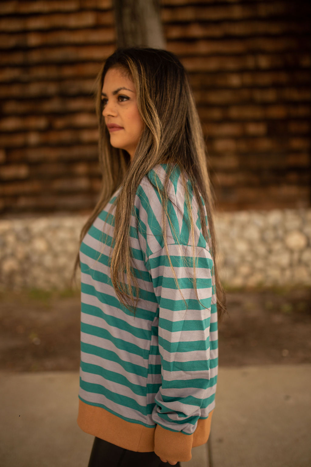 Teal and gray striped sweatshirt with caramel ribbed cuffs and hem, shown in natural outdoor lighting.