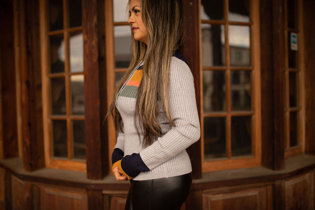 Soft ribbed long sleeve top featuring warm-toned color block stripes across the chest and sleeves, displayed in natural outdoor lighting.