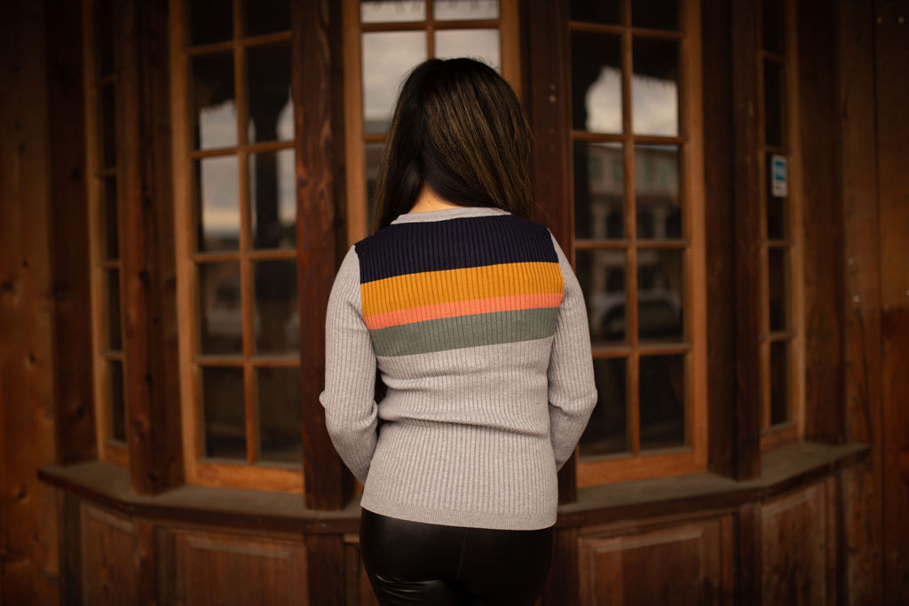 Soft ribbed long sleeve top featuring warm-toned color block stripes across the chest and sleeves, displayed in natural outdoor lighting.